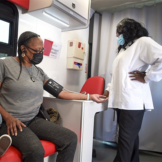 A female medical professional checking a woman's blood pressure at a project health event