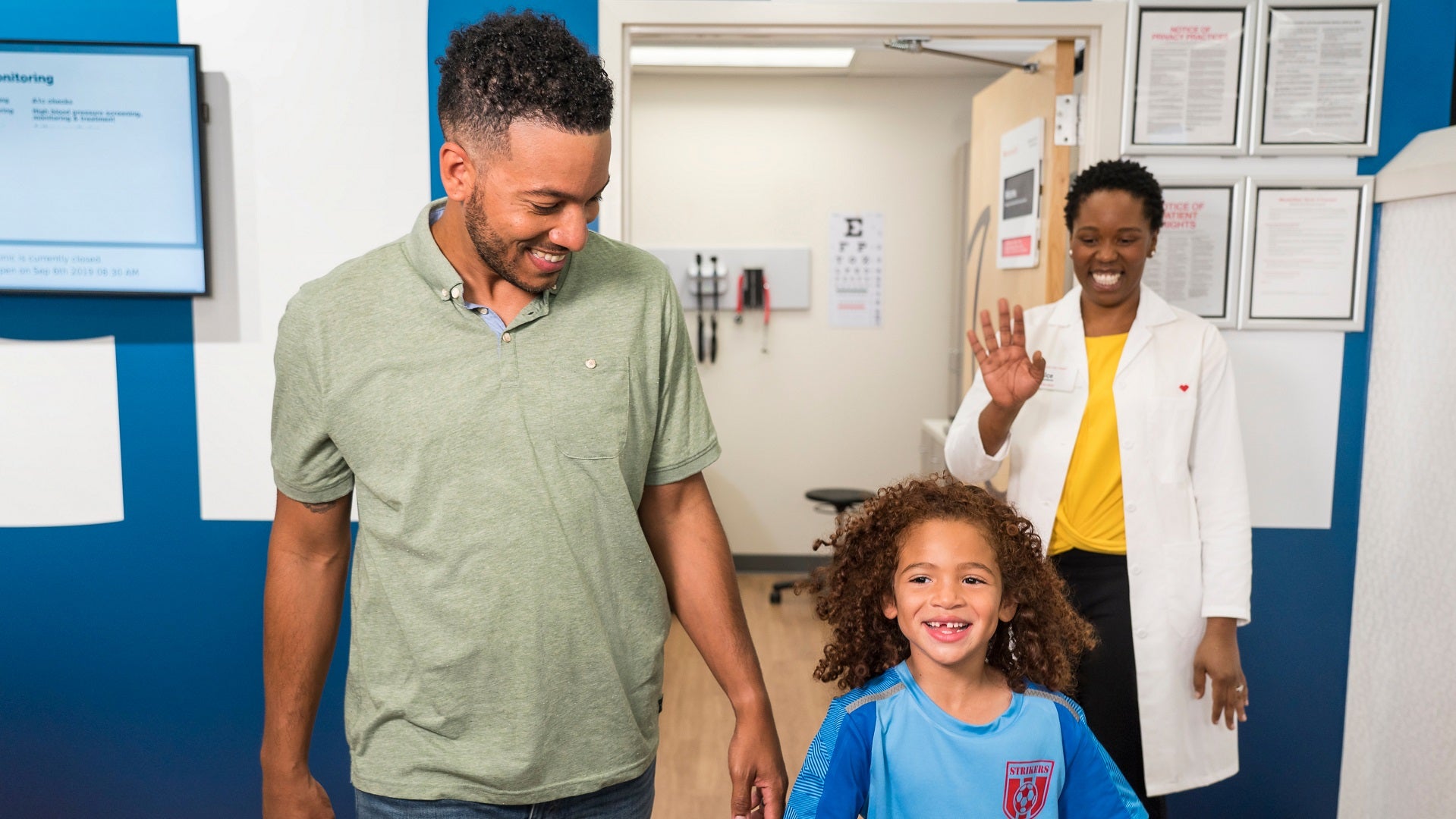Dad and daughter walk out of MinuteClinic office with CVS Health employee waving goodbye
