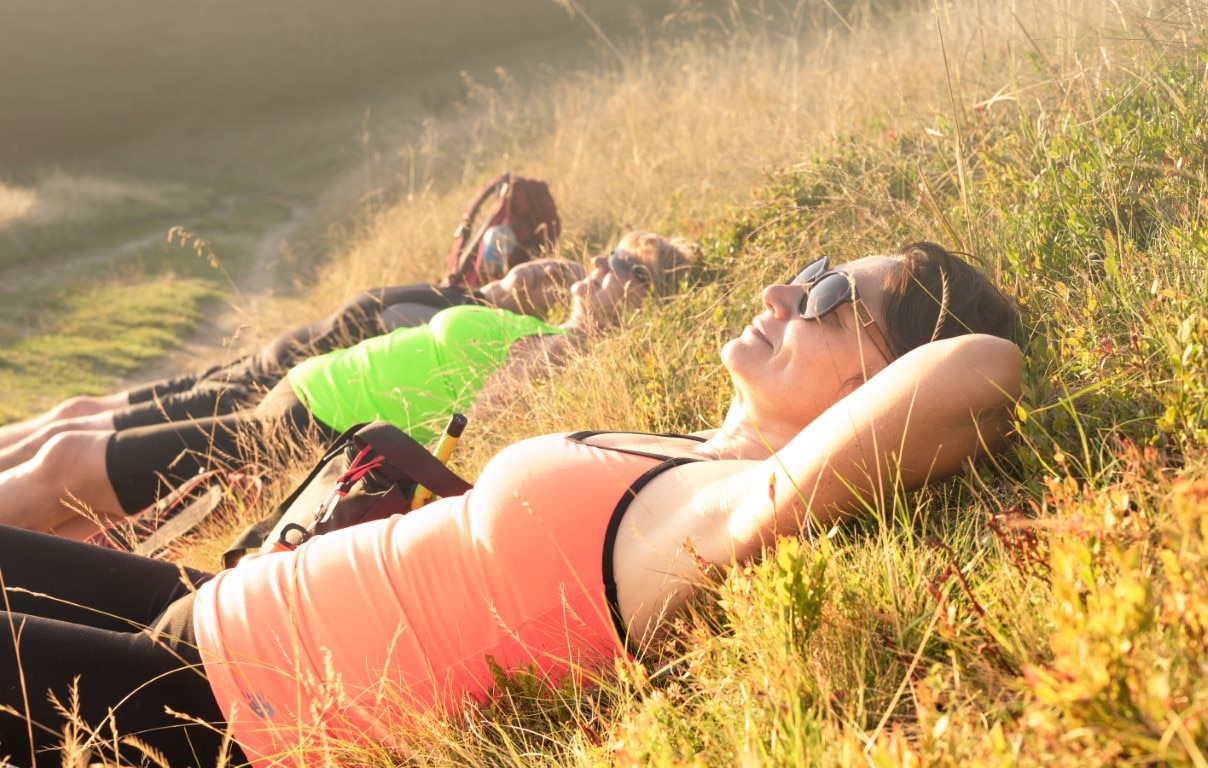A group of women relaxing in the grass after a hike.