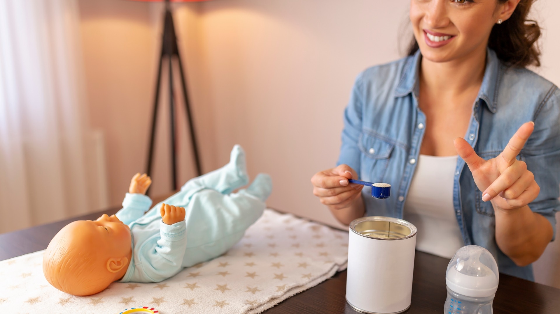 Woman sitting behind a baby doll laying on a table