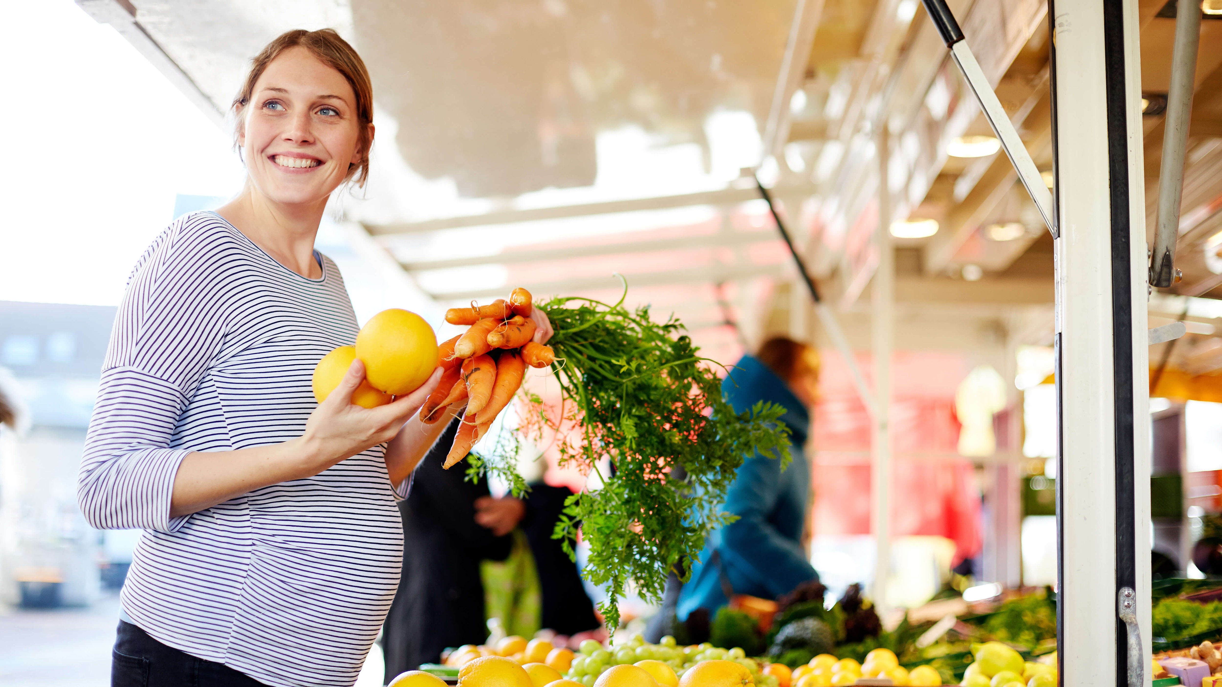 A pregnant woman shopping at an outdoor produce market