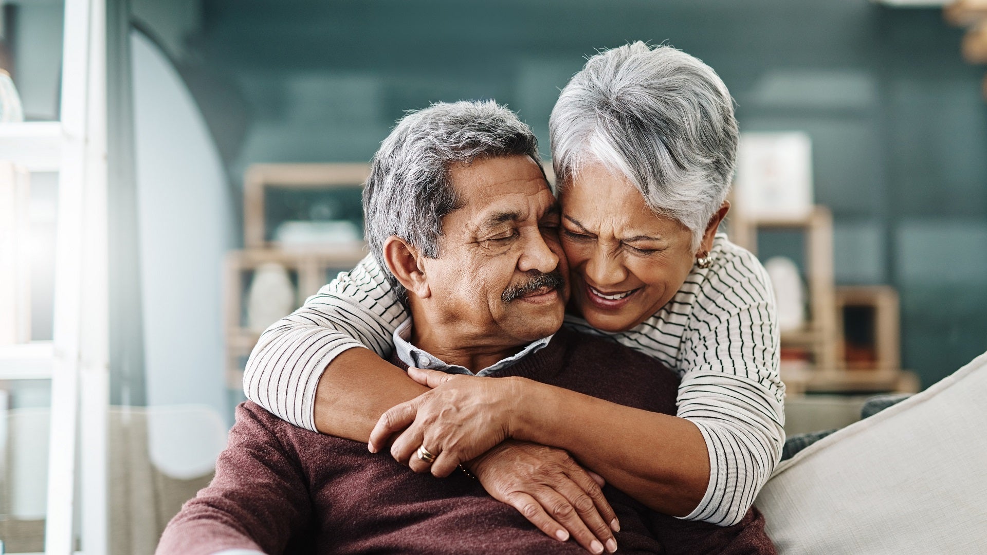 Cropped shot of a cheerful elderly woman hugging her husband who's in a wheelchair at home during the day