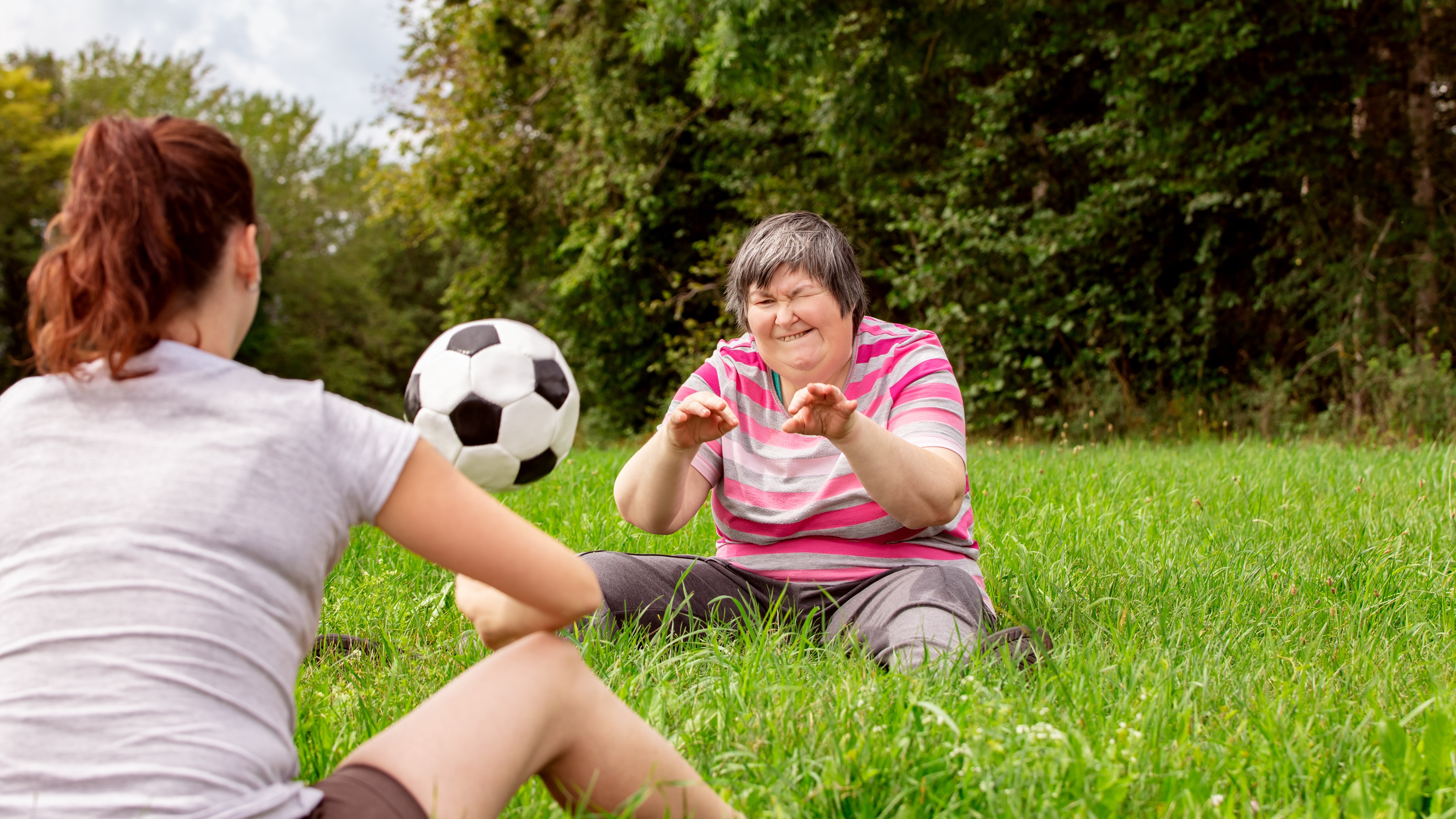 Two people outdoors throwing a soccer ball