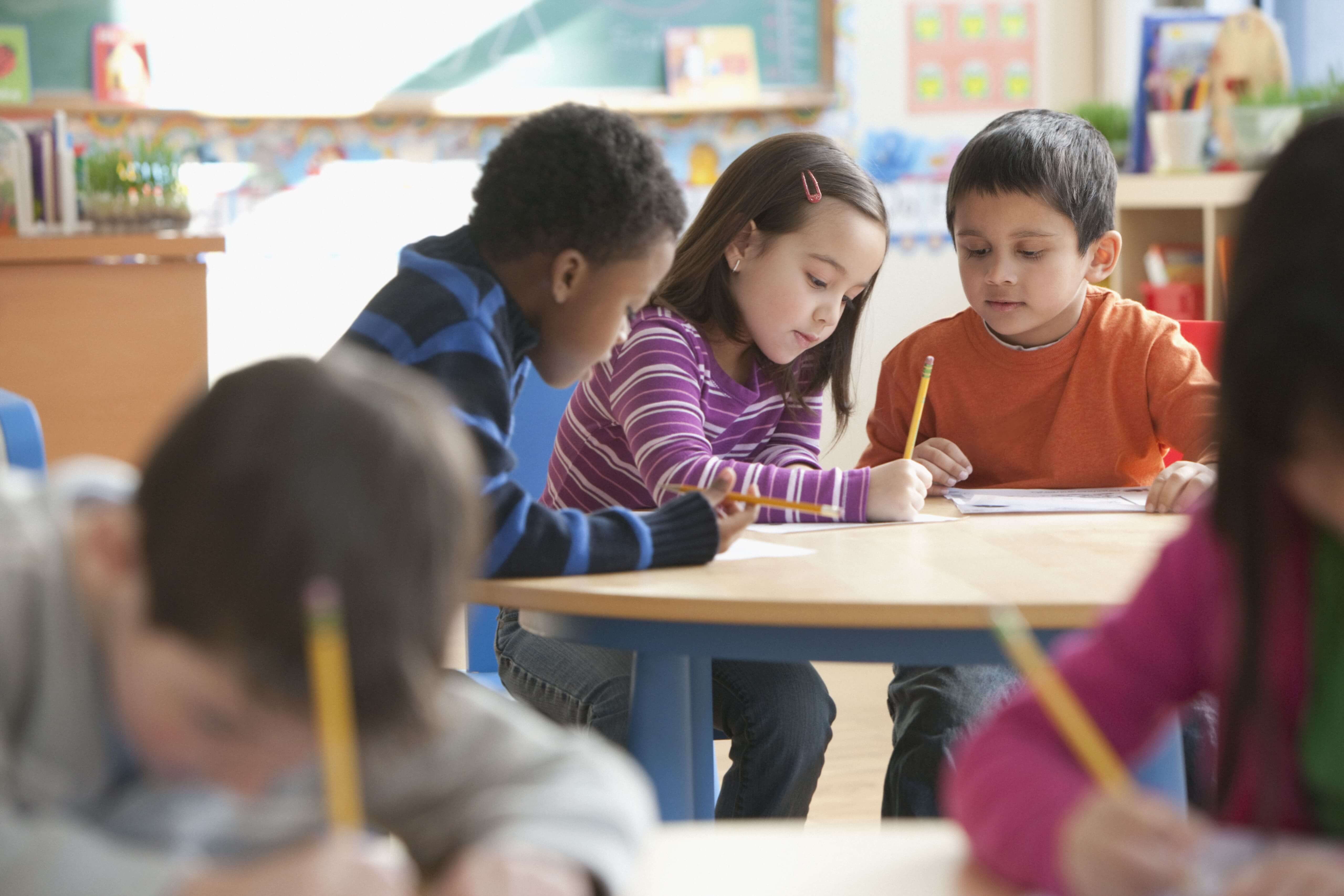 Three children sitting at a table in a classroom