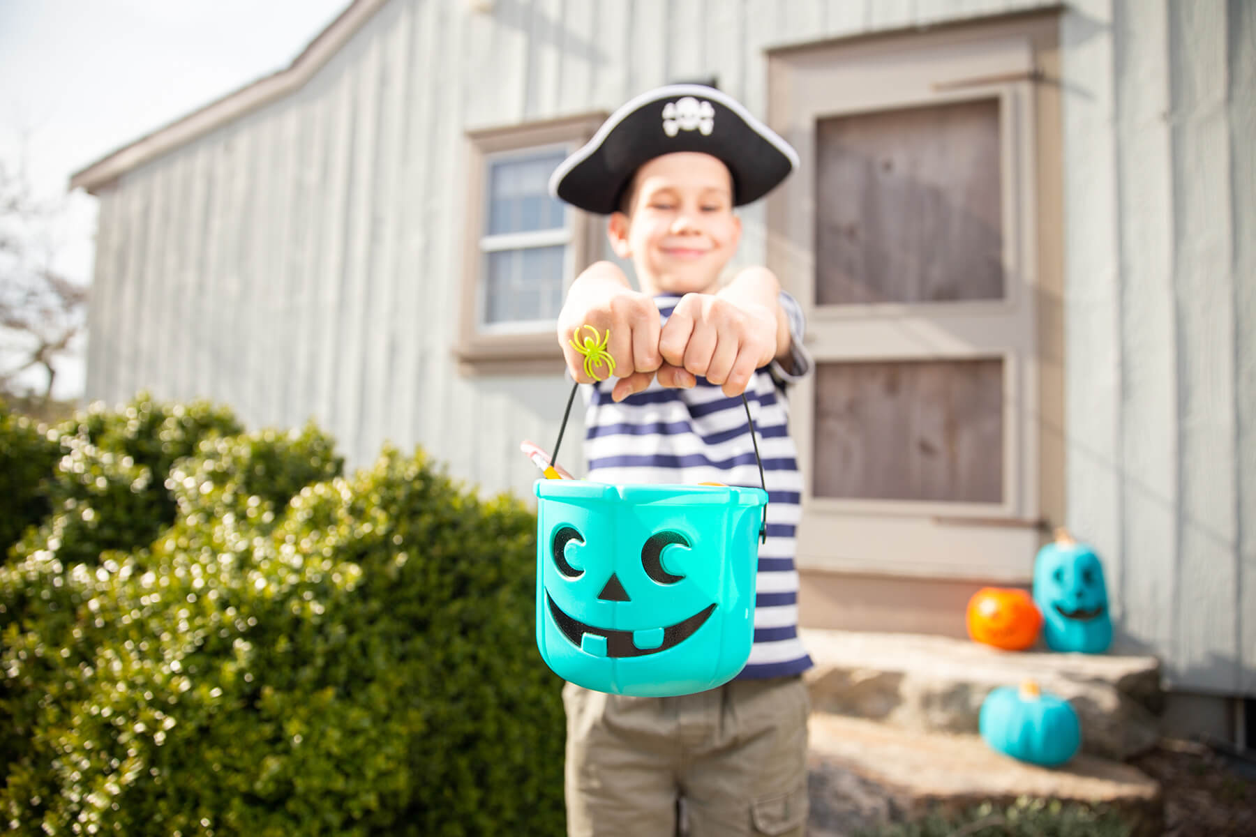 Child holding a teal trick-or-treating pail