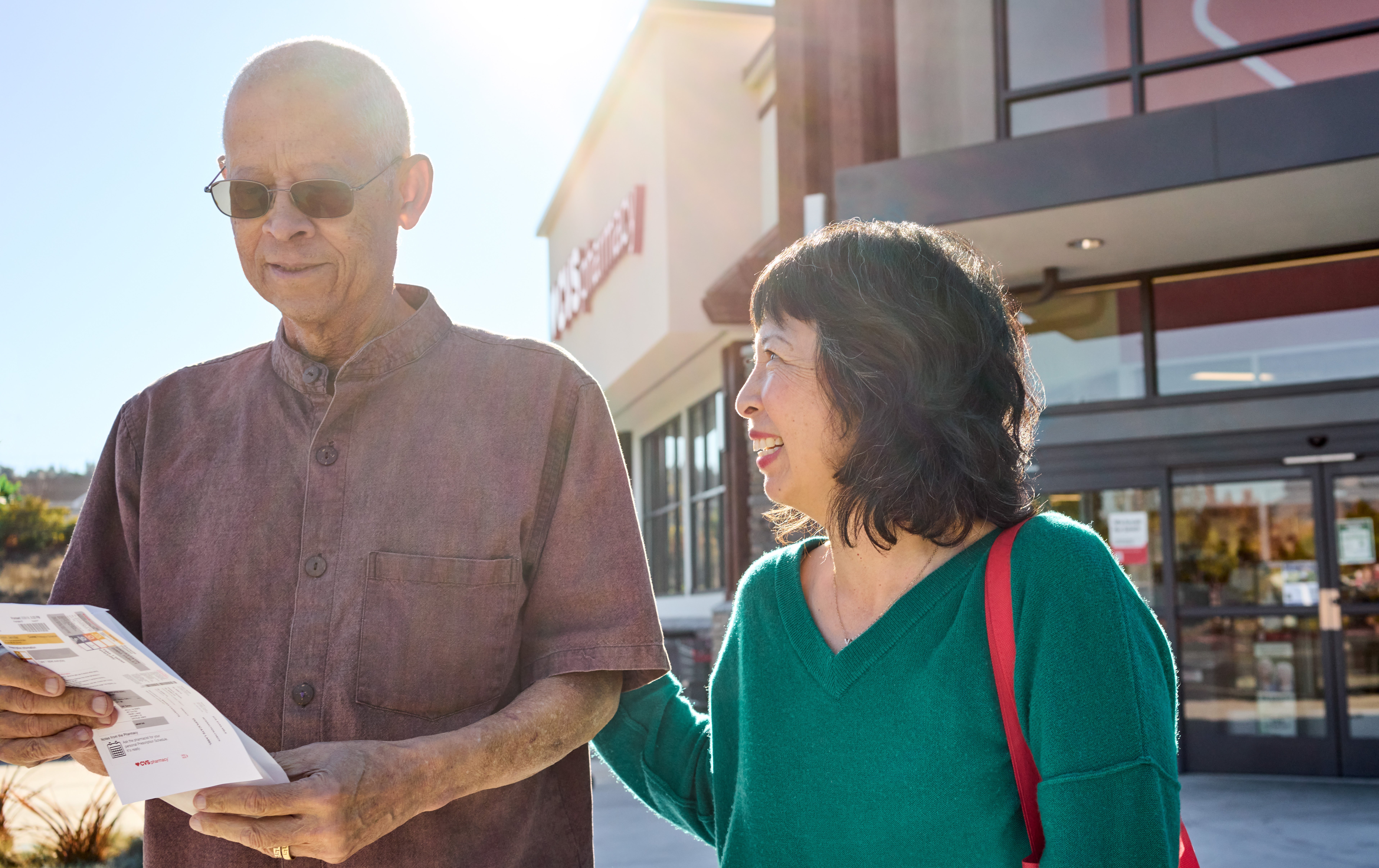 Two people standing in front of a CVS Pharmacy location discussing medication