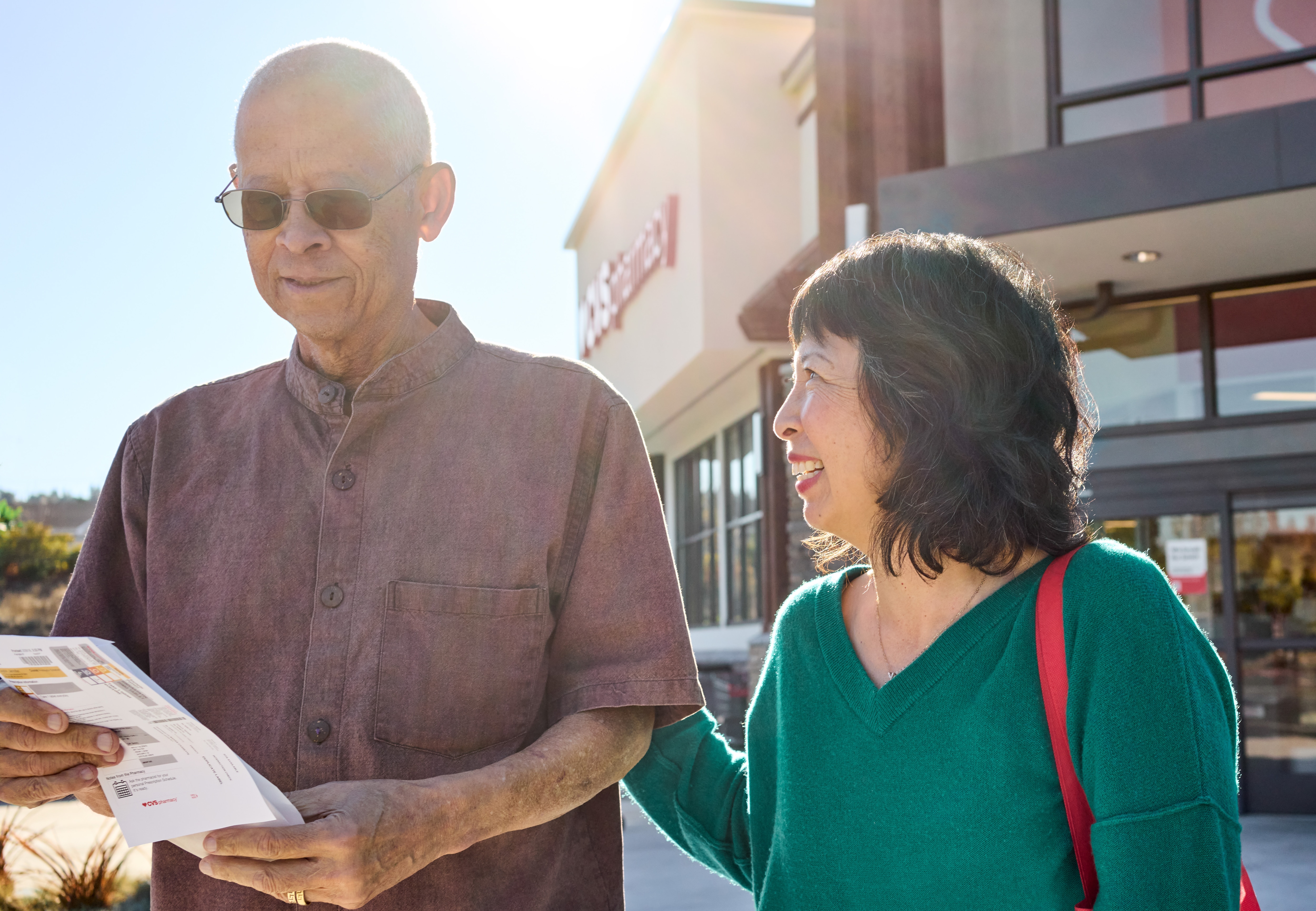 Two people standing in front of a CVS Pharmacy location discussing medication