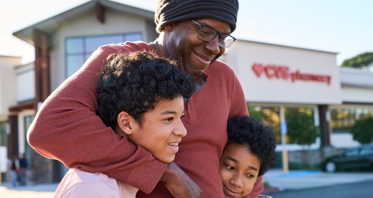 Man standing in front of CVS Pharmacy with two young boys