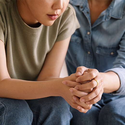 Mother and daughter sitting on couch holding hands