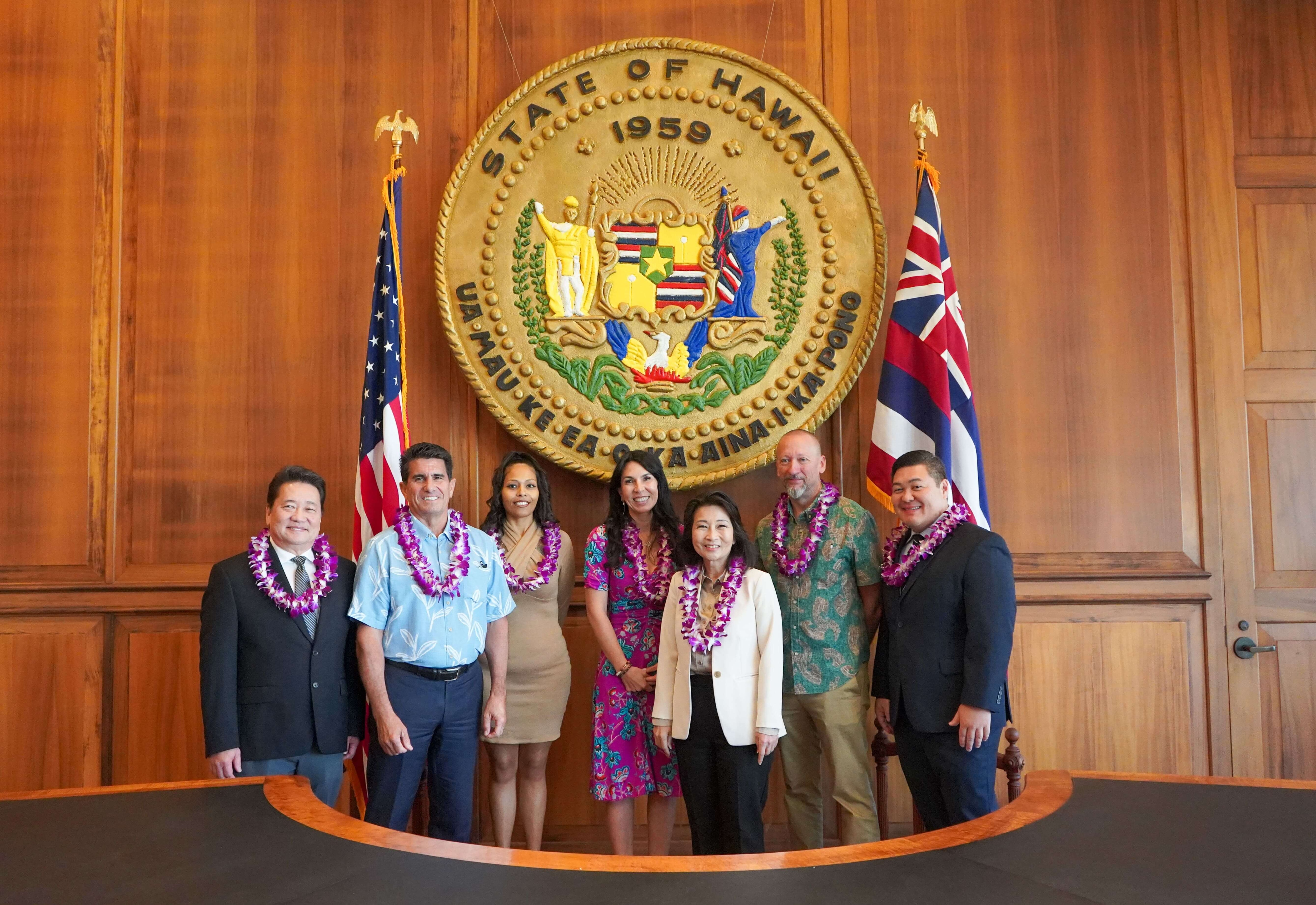 People standing in front of Hawaii state seal