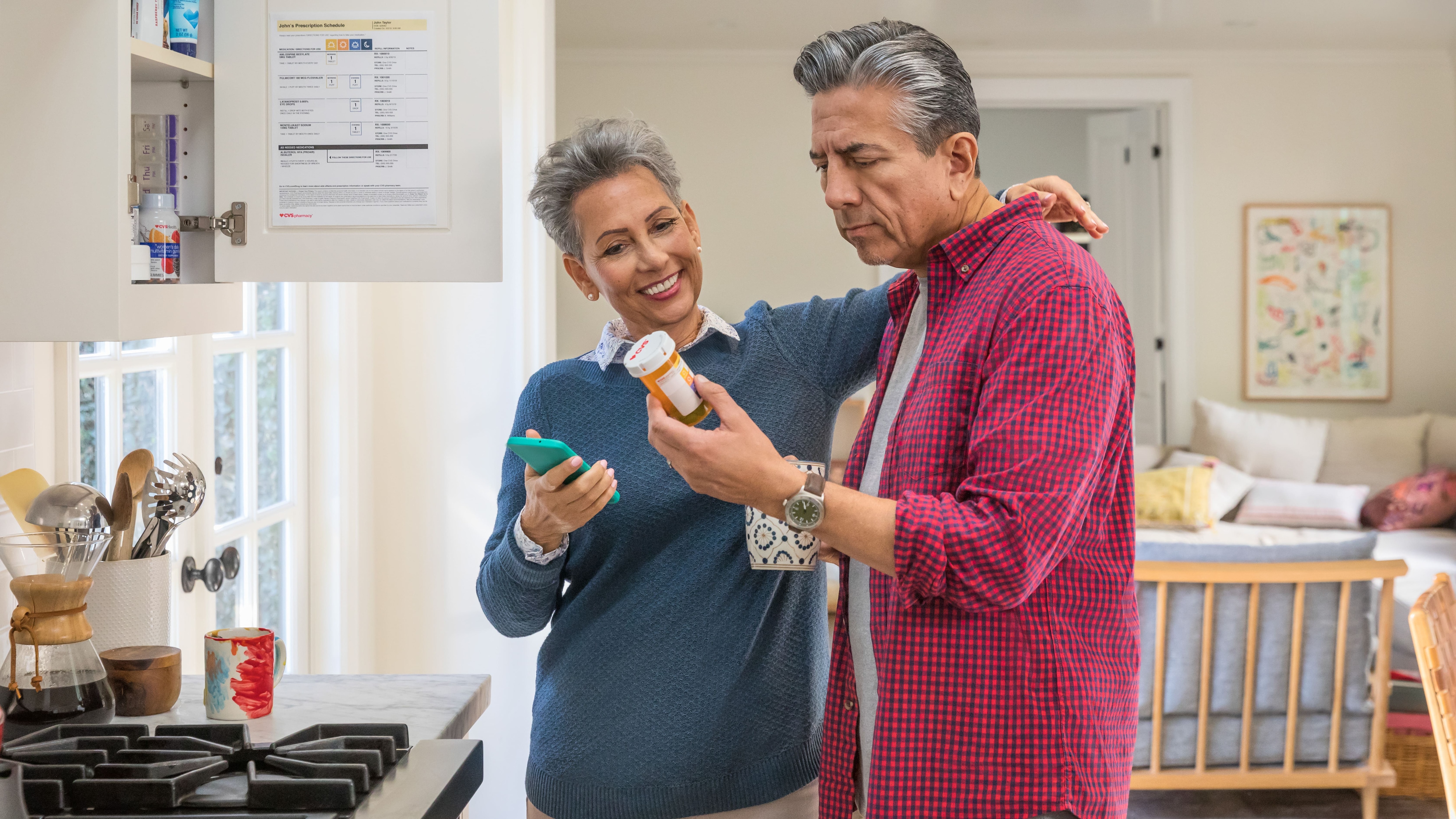 Man and woman looking at prescription pill bottle in kitchen