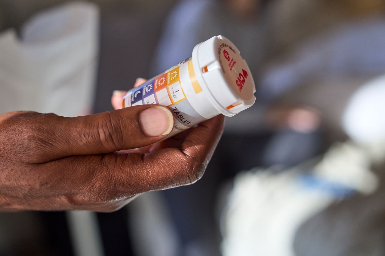 Photo depics hand holding prescription bottle
