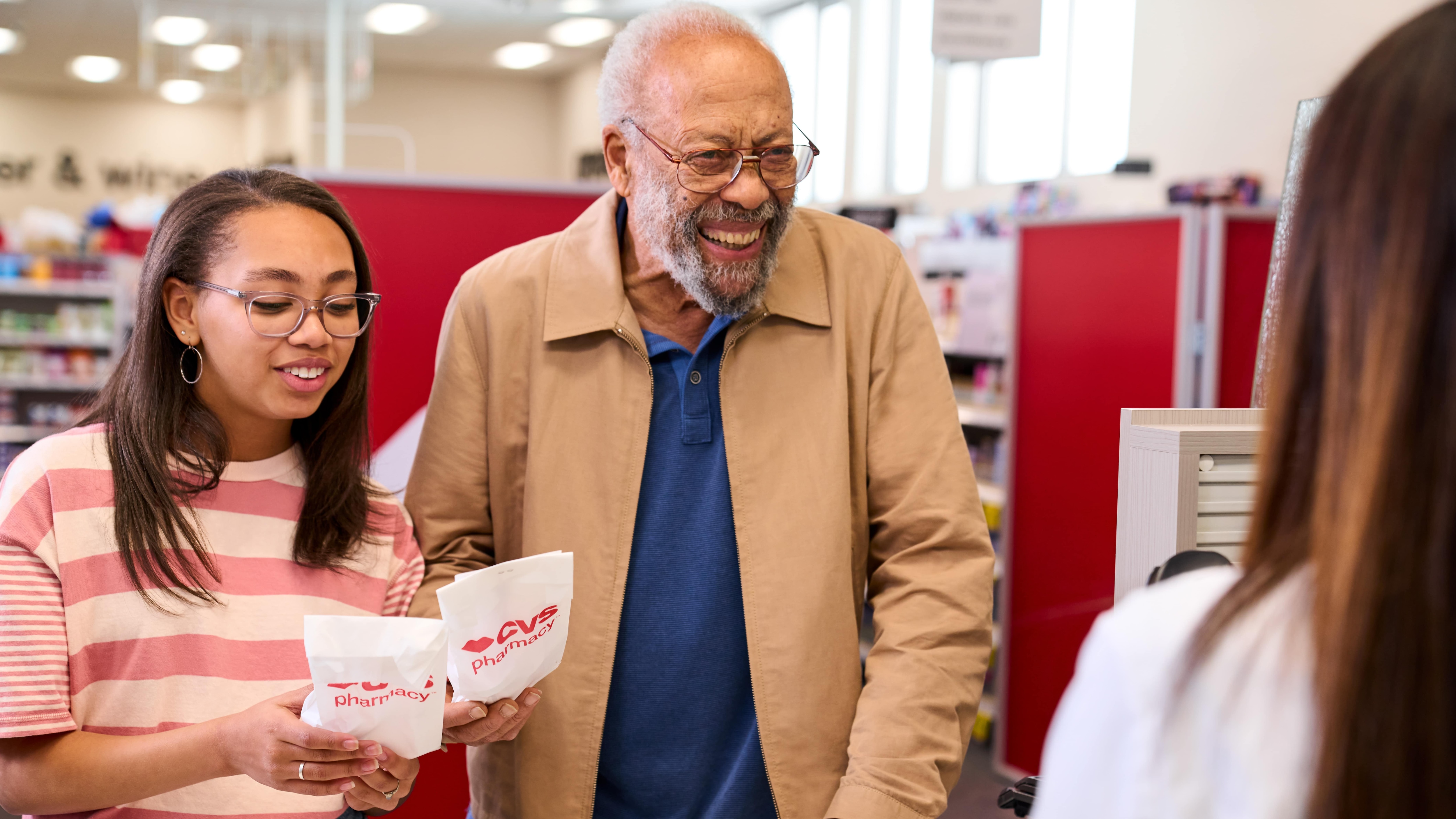 Older man and young woman picking up prescriptions from the pharmacy