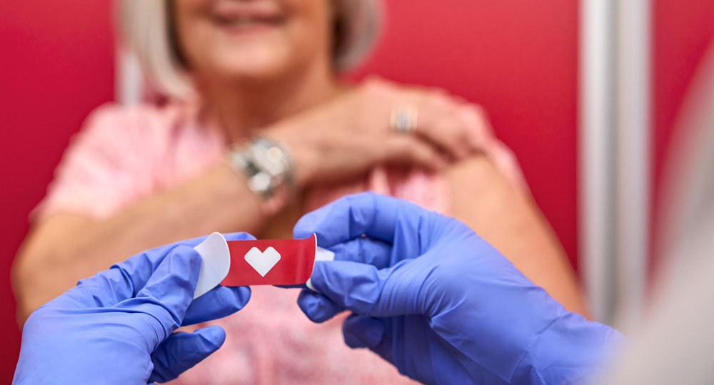 Physician putting bandaid on after giving vacination to patient
