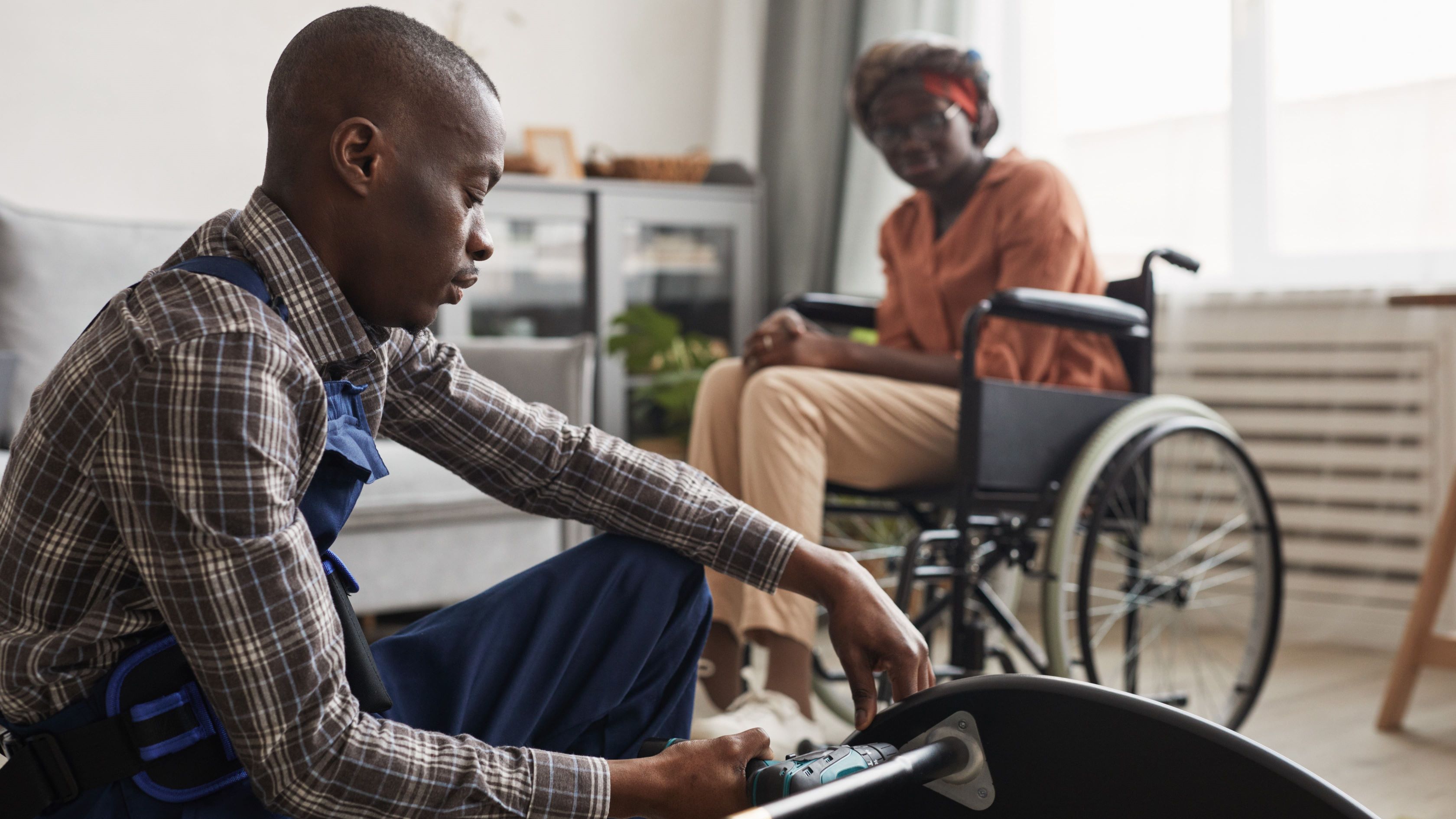 Woman in wheelchair watching man repair a table