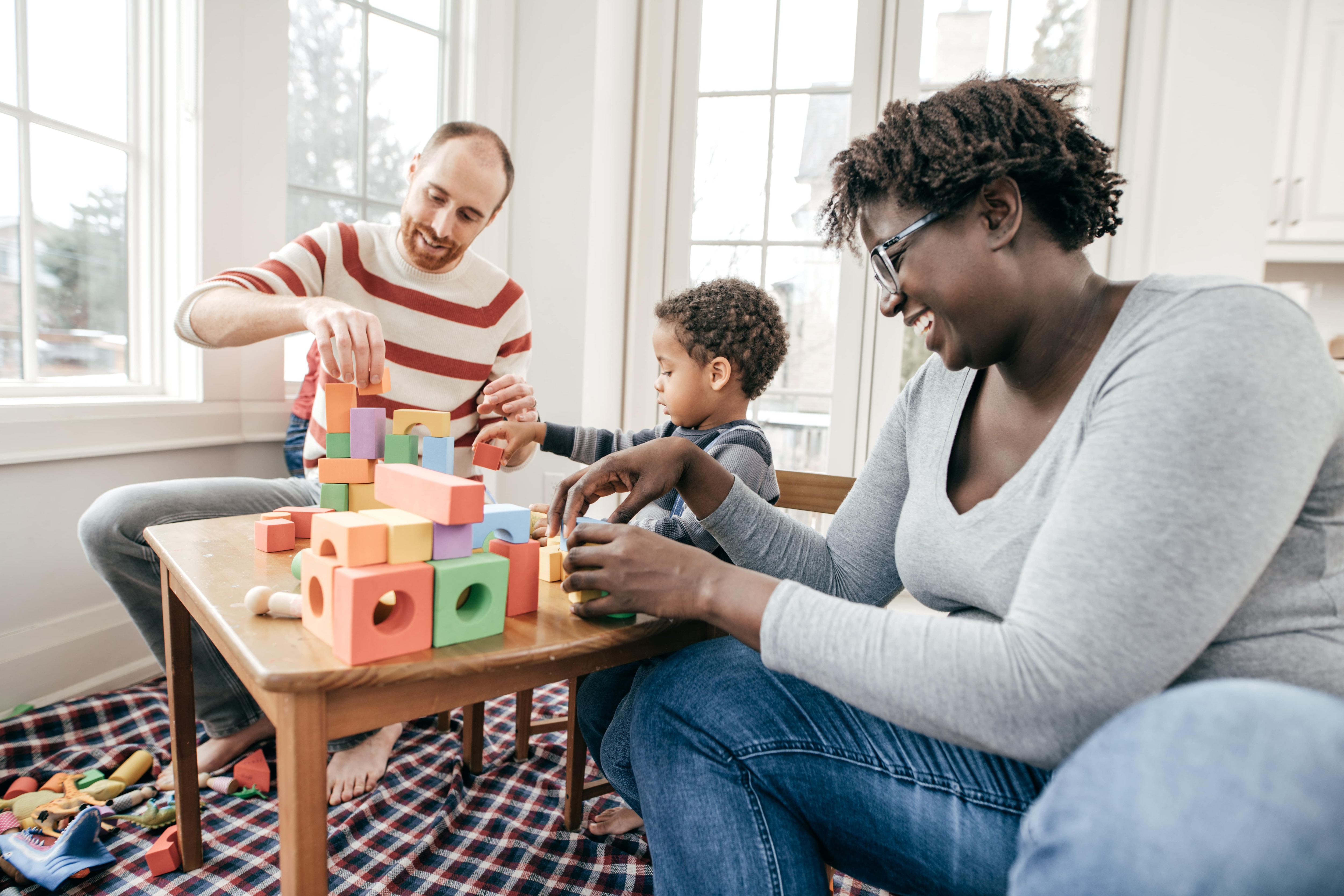 Parents and young son playing with blocks in their new home