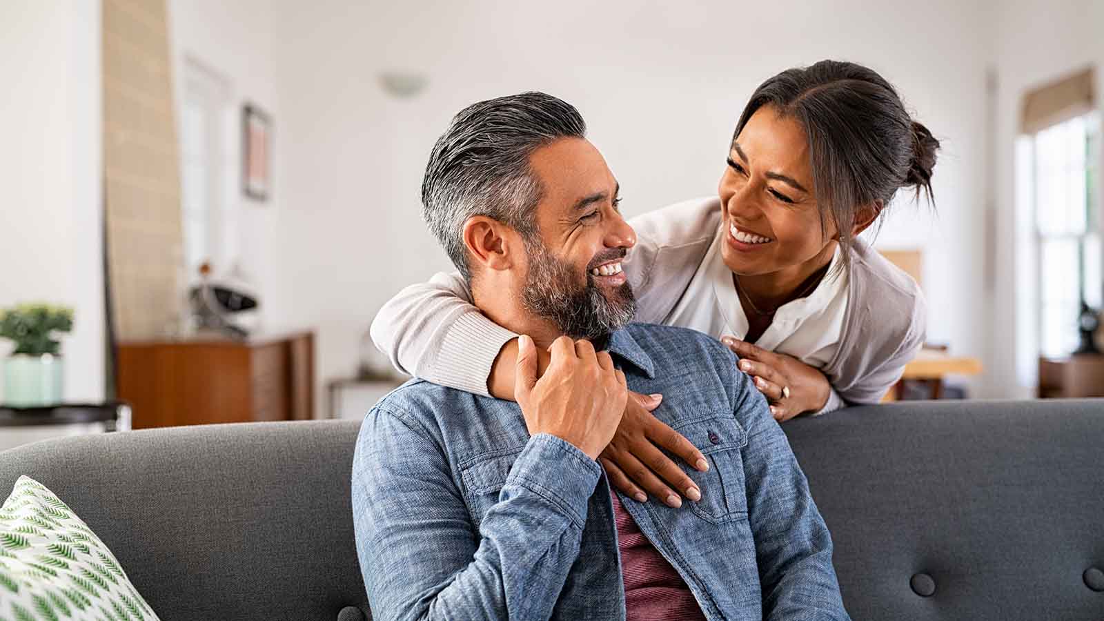 Woman with arm around man sitting on a. couch