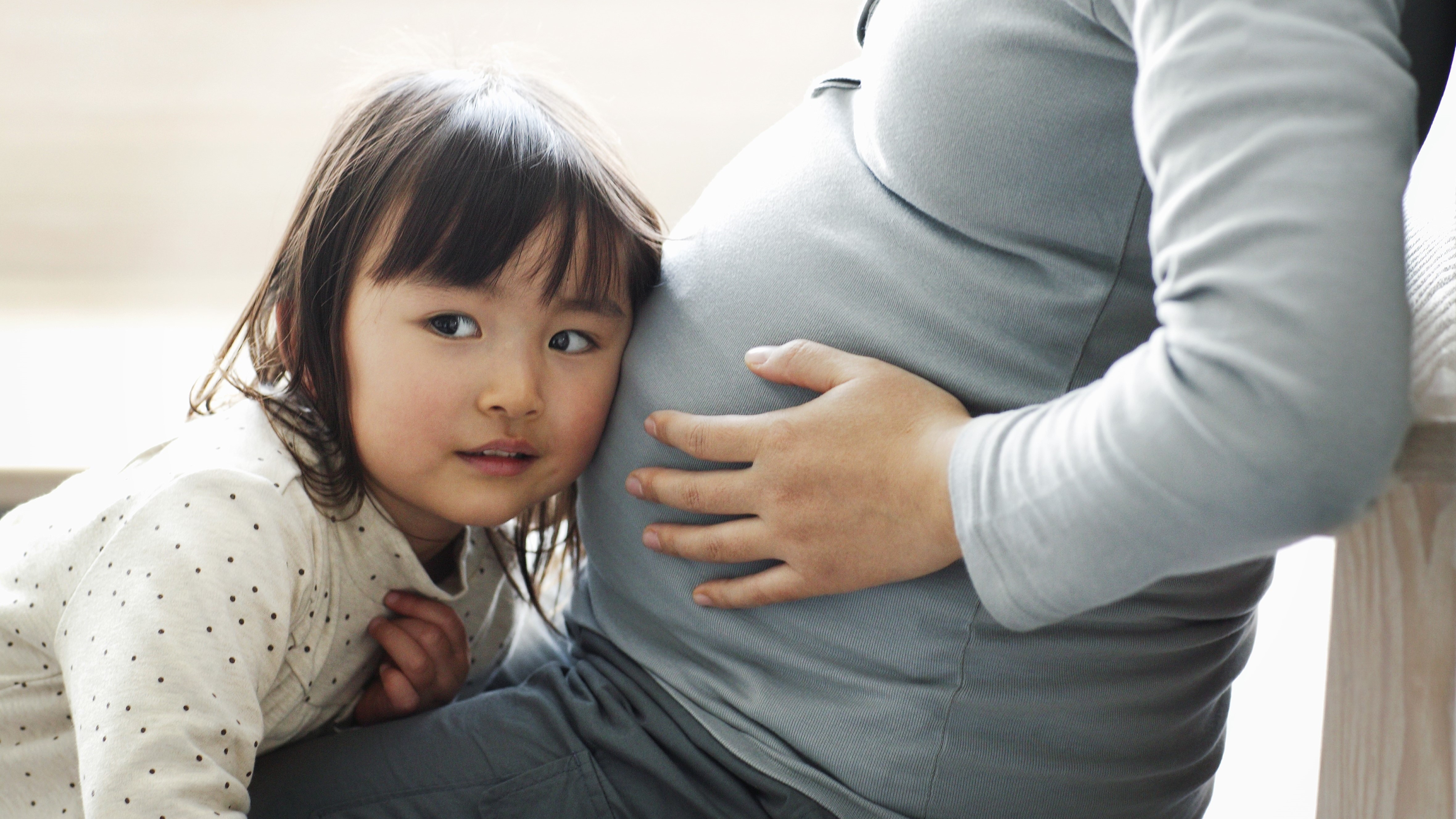 A child sitting with their pregnant mother