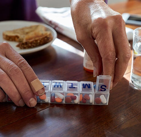Grandmother taking medication from pill organizer