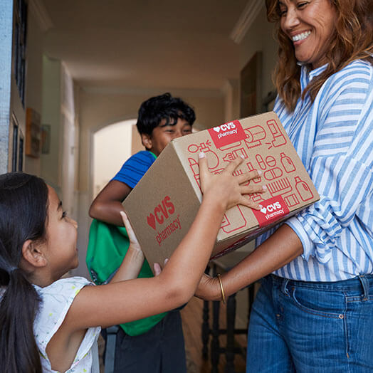 Mother and children holding CVS delivery box at front door