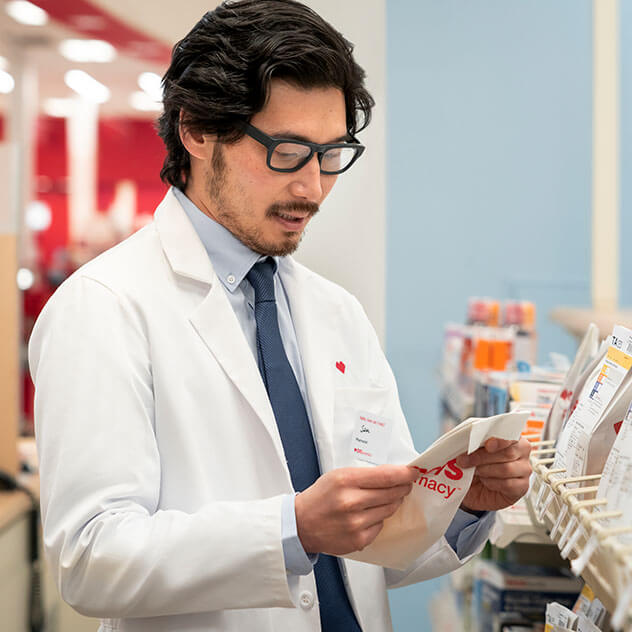 Male pharmacist reviewing prescription information in pharmacy