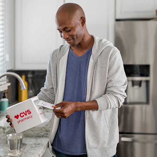 Man opening CVS prescription in kitchen