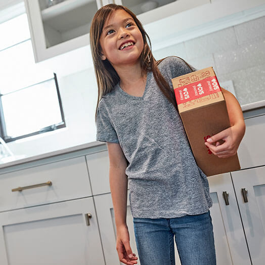 Child holding CVS delivery box in kitchen