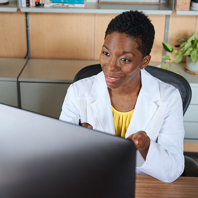 Female medical professional in front of a monitor talking with a patient virtually