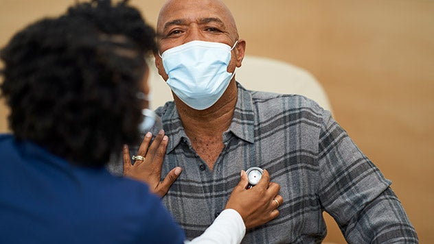 Female medical professional checking male patient's heart rate with stethoscope