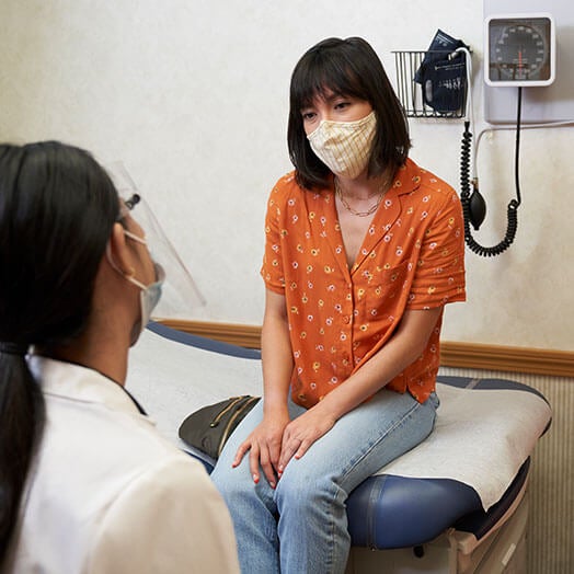 Female doctor talking to female patient in exam room