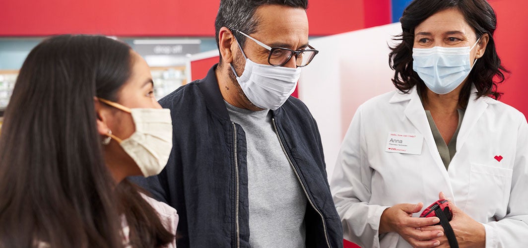 Two women and a man wearing masks while speaking to each other