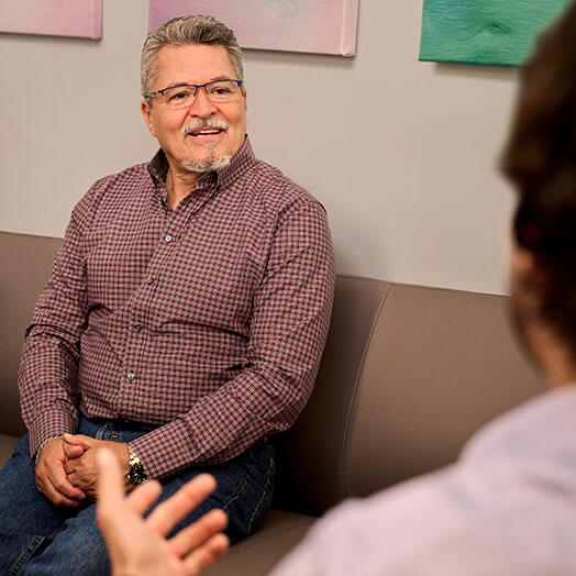 Male on couch having conversation with another person