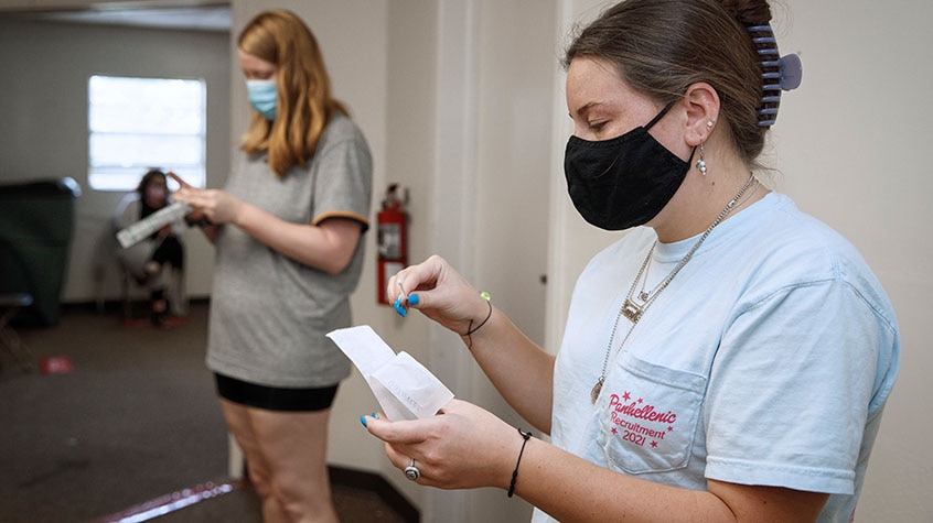 Women standing in a waiting room wearing masks reading covid information