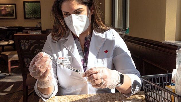 CVS Pharmacist filling syringe with medicine