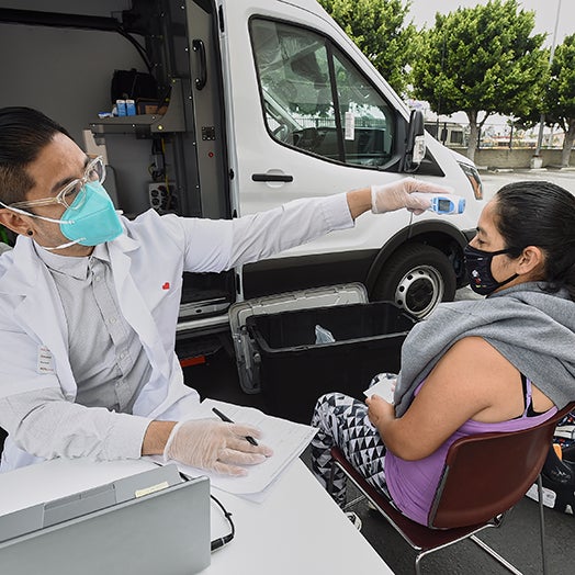 Medical professional taking patient in wheelchairs temperature