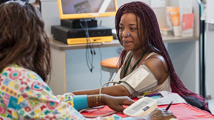 Woman checking patient's blood pressure